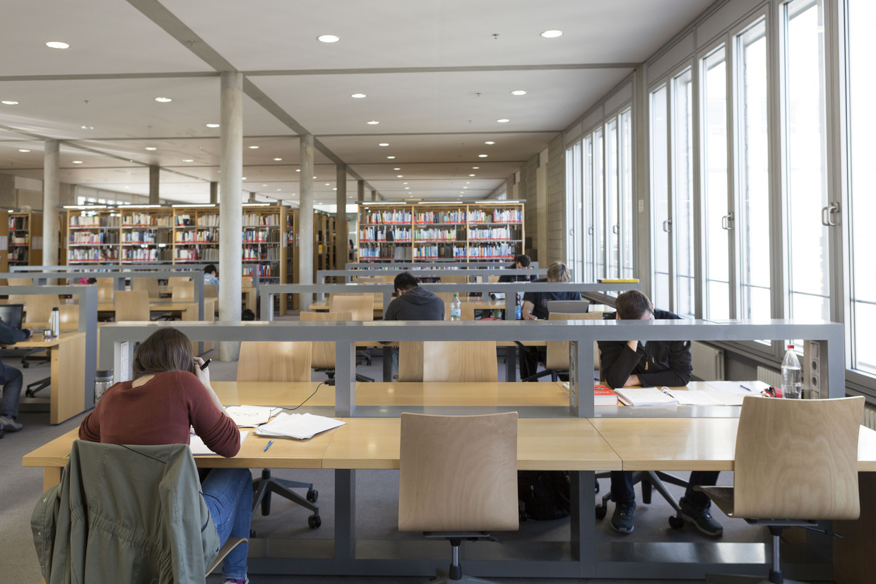 Studierende lernen in ruhigem, modernem Lesesaal einer Universitätsbibliothek.
