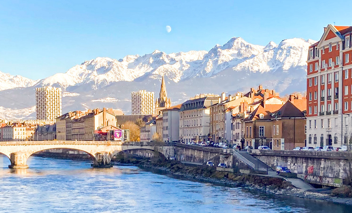 Sicht auf Grenoble. Fluss und Häuserfront sowie Berge im Hintergrund