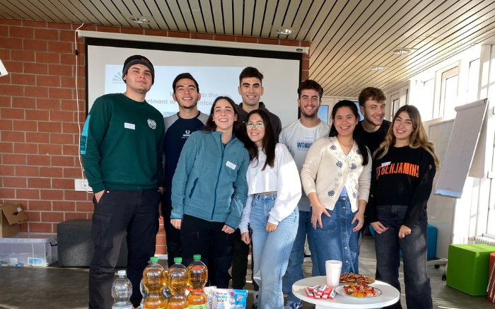 Internationale Studierende stehen in einem Zimmer und lächeln in die Kamera