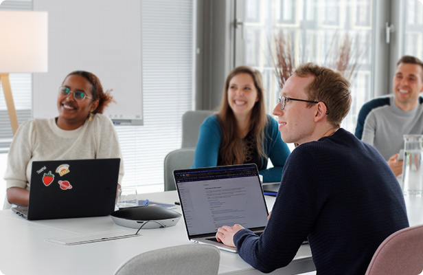 Vier Junge Leute sitzen an einem Tisch und arbeiten am Laptop